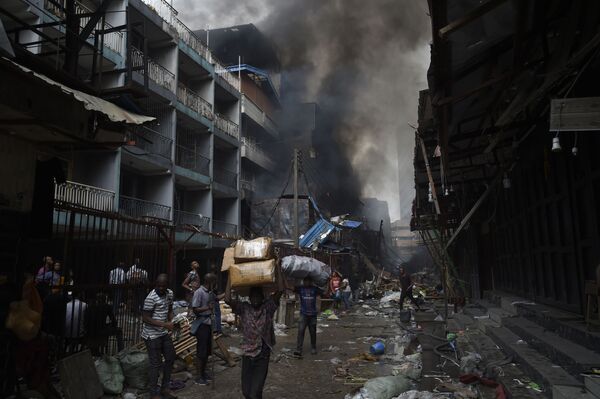 Люди несут товары, спасенные от пожара, в районе рынка Балогун в Лагосе - Sputnik Южная Осетия