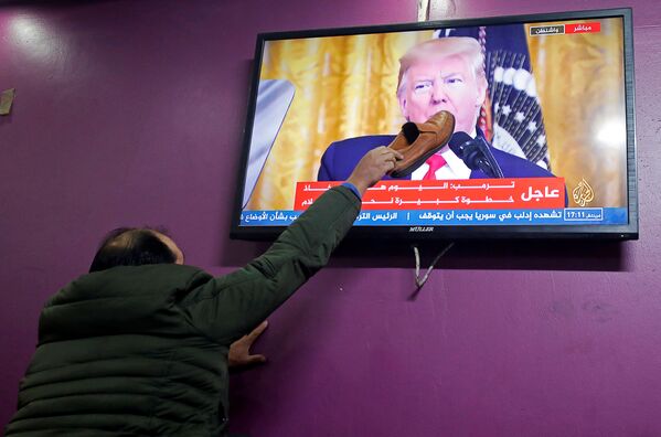 Палестинец прикладывает ботинок к экрану телевизора в кафе города Хеврон, по которому Дональд Трамп рассказывает о своем плане ближневосточного урегулирования - Sputnik Южная Осетия