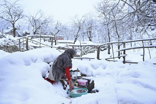 Женщина моет посуду на окраине Сринагара, где выпал снег - Sputnik Южная Осетия