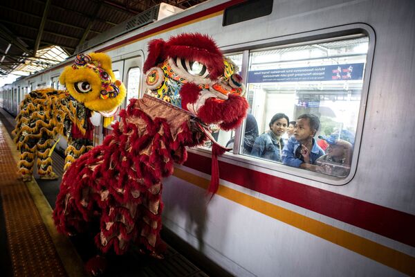  Пассажиры смотрят из окна поезда на праздничных львов во время празднования китайского лунного Нового года в Джакарте, Индонезия - Sputnik Южная Осетия