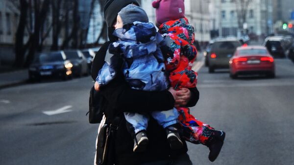 Женщина с двумя детьми на руках переходит дорогу. Архивное фото - Sputnik Южная Осетия