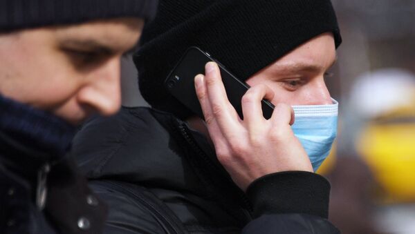 Молодой человек в медицинской маске разговаривает по телефону - Sputnik Южная Осетия