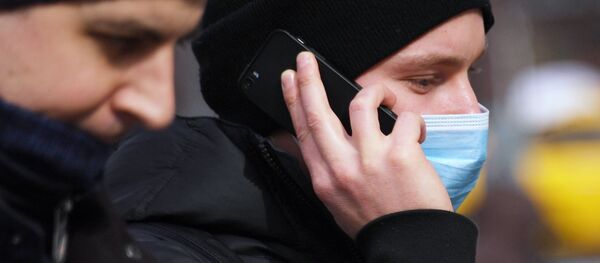 Молодой человек в медицинской маске разговаривает по телефону - Sputnik Южная Осетия