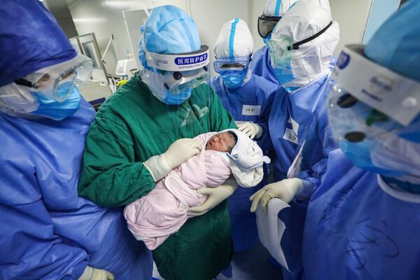 Врач держит новорожденного ребенка в отделении гинекологии и акушерства для будущих мам, инфицированных COVID-19 - Sputnik Южная Осетия