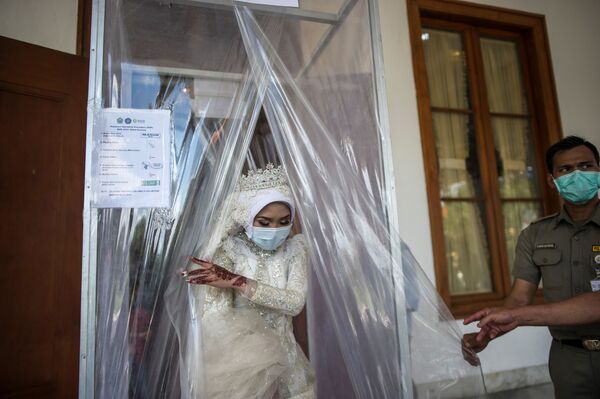 Индонезийская невеста в маске после дезинфекции во время свадебной церемонии в городе Сурабая - Sputnik Южная Осетия