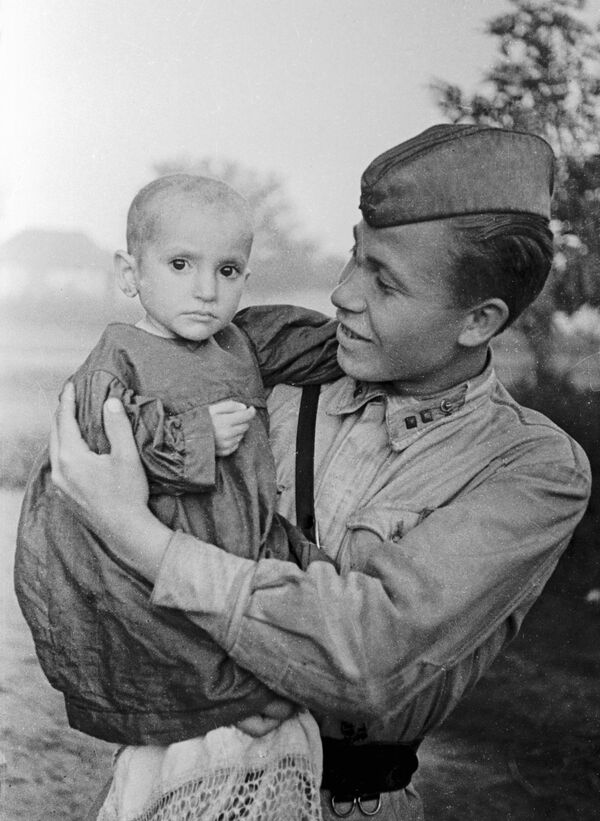 Советский офицер  держит на руках спасенную им девочку из деревни Эльхотово, 1942 год - Sputnik Южная Осетия