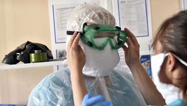 Врач одевает защитный комбинезон, очки, маску, перчатки - Sputnik Южная Осетия