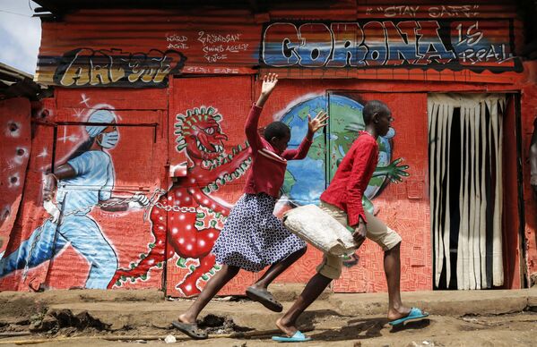 Бегущие дети на фоне посвященного коронавирусу граффити в трущобах Киберы в Найроби, Кения - Sputnik Южная Осетия