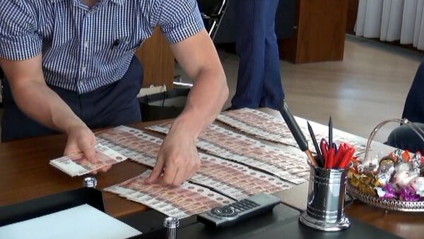 Сотрудник правоохранительных органов раскладывает деньги на столе в кабинете директора банка - Sputnik Южная Осетия
