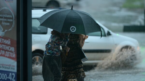 Женщины идут под зонтом во время сильного дождя в Грозном - Sputnik Южная Осетия