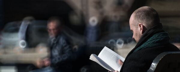 Мужчина читает книгу на скамейке в парке Мужчина читает книгу на скамейке в парке - Sputnik Южная Осетия