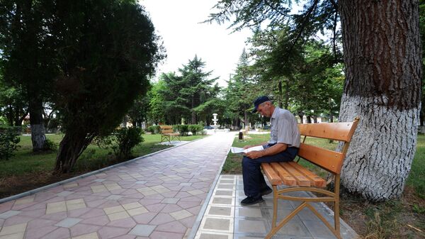 Мужчина читает газету на лавочке в центральном парке города Цхинвал. - Sputnik Южная Осетия