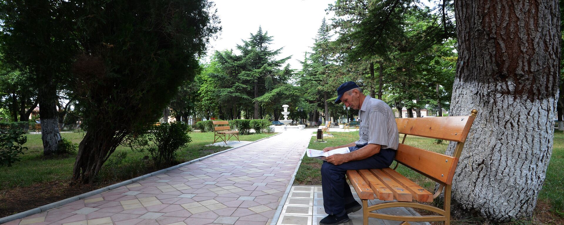 Мужчина читает газету на лавочке в центральном парке города Цхинвал. - Sputnik Южная Осетия, 1920, 25.11.2022