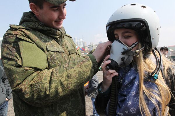 Военнослужащий помогает девушке примерить летный шлем на выставке боевой техники на центральной площади Владивостока - Sputnik Южная Осетия