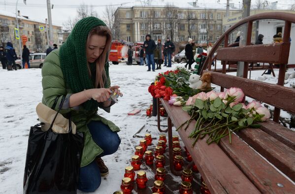 Женщина зажигает свечу возле здания торгового центра «Зимняя вишня» в Кемерово, где произошел пожар - Sputnik Южная Осетия