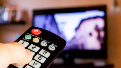 Рука с пультом напротив телевизора