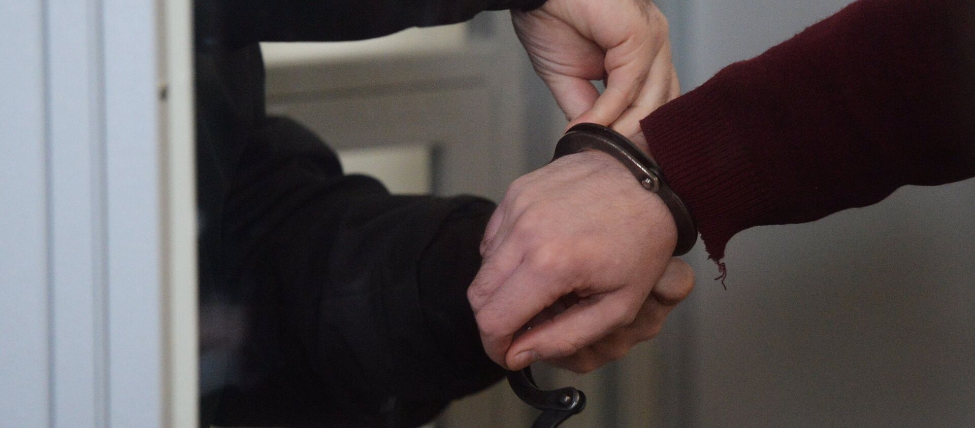 Сотрудник правоохранительных органов снимает наручники   - Sputnik Южная Осетия, 1920, 21.07.2021