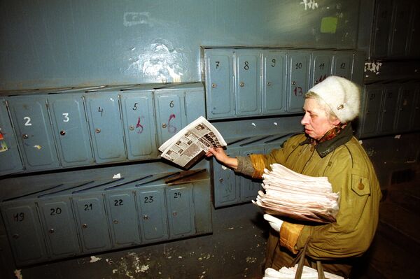Почтальон раскладывает свежие газеты по почтовым ящикам в подъезде жилого дома - Sputnik Южная Осетия