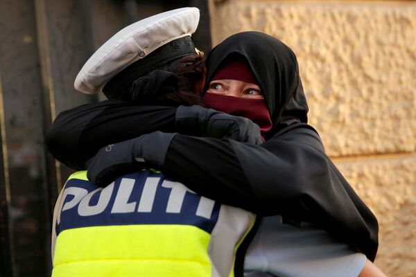 Испуганная женщина обнимает полицейского во время демонстрации за запрет на ношение хиджабов в Копенгагене, Дания - Sputnik Южная Осетия