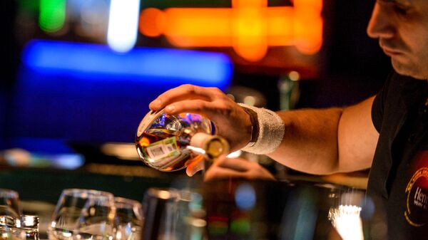 Бармен разливает напитки, стоя за барной стойкой в клубе - Sputnik Южная Осетия