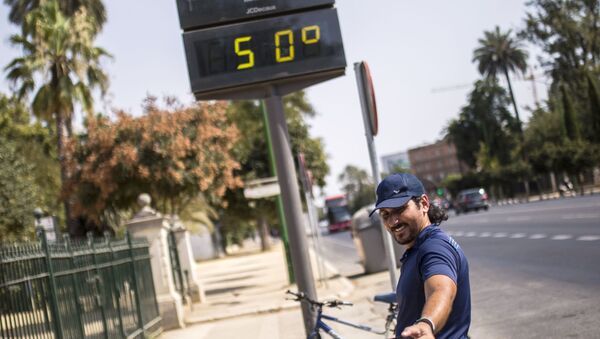 Мужчина фотографируется у электронного табло, которое показывает температуру +50 в Севилье - Sputnik Южная Осетия