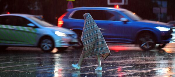 Прохожий переходит дорогу во время дождя в Москве, накрывшись пледом Прохожий переходит дорогу во время дождя в Москве, накрывшись пледом - Sputnik Южная Осетия