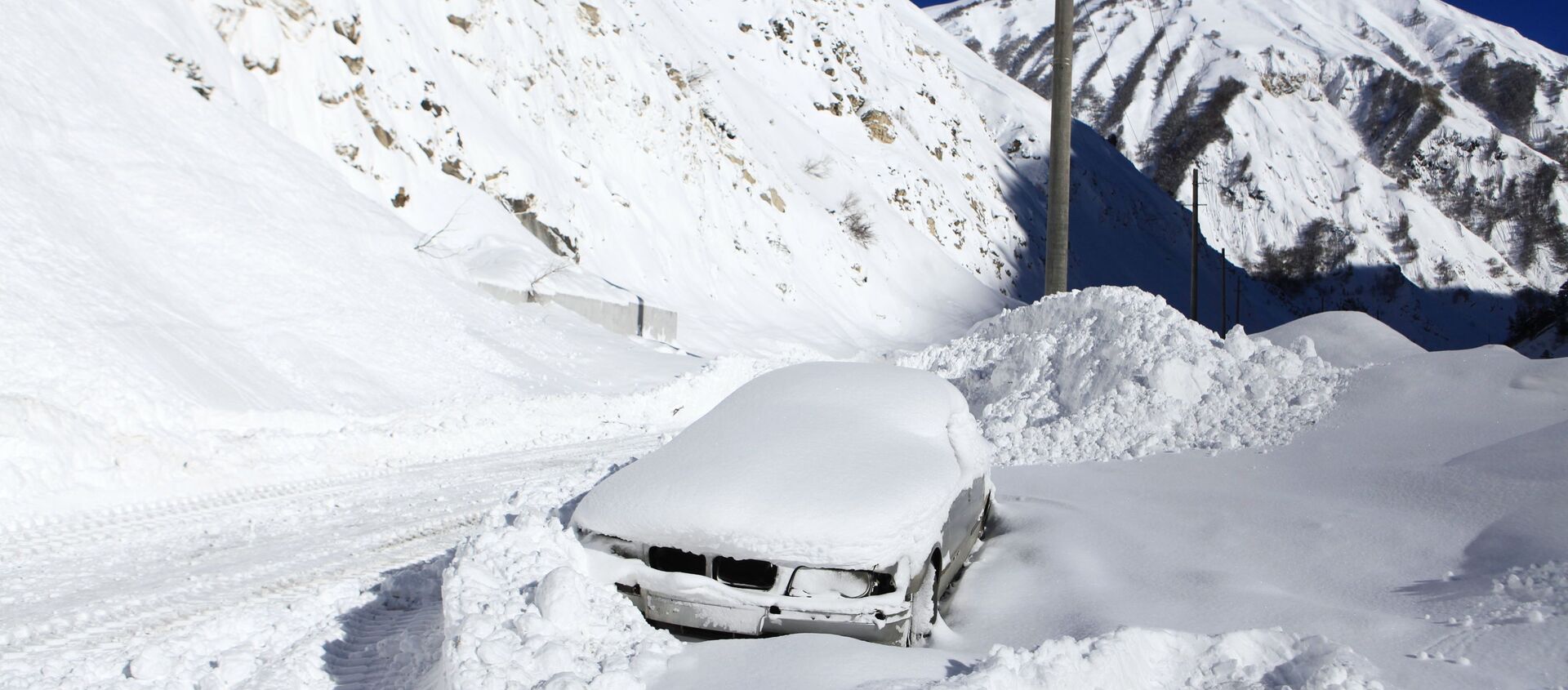 Заваленный снегом автомобиль на обочине автомобильной дороги Транскавказской магистрали в Северной Осетии, перекрытой из-за схода снежных лавин - Sputnik Южная Осетия, 1920, 24.02.2021