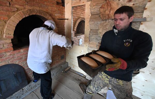 Владелец крестьянского фермерского хозяйства Андрей Шаплов во время закладки форм с тестом в печь - Sputnik Южная Осетия