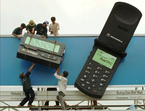 Рабочие размещают гигантский пейджер рядом с гигантским мобильным телефоном с рекламой телекоммуникационных продуктов Motorola в городе Хошимин, 1996 - Sputnik Южная Осетия