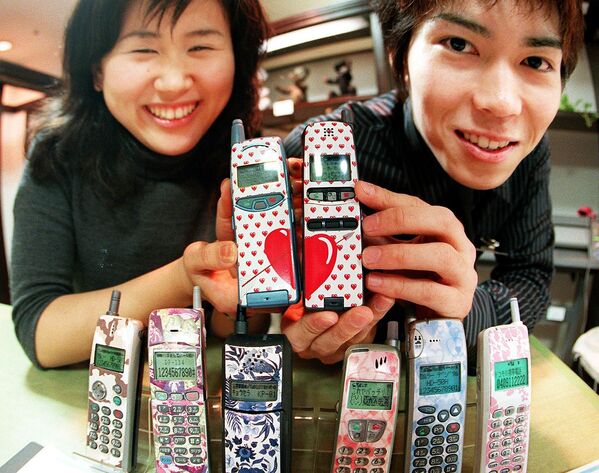 Молодая японская пара демонстрирует свои мобильные телефоны с дизайнерскими клеймами в универмаге Токи - Sputnik Южная Осетия