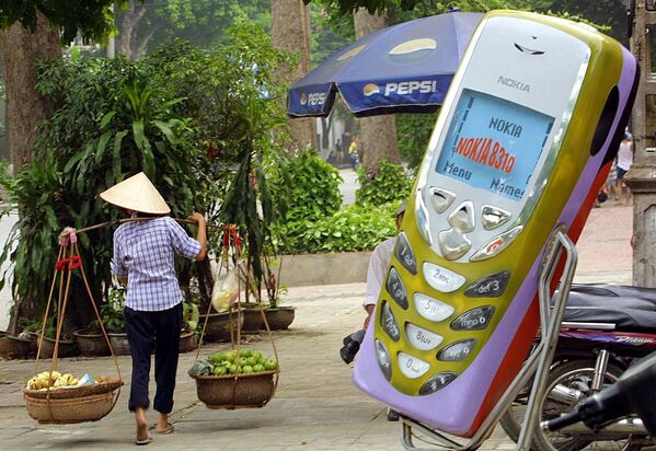 Продавец фруктов проходит мимо магазина мобильных телефонов в Ханое, Вьетнам. 2002 год - Sputnik Южная Осетия