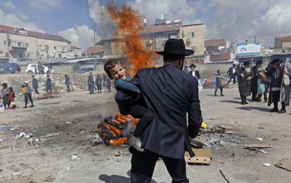 Ультраортодоксальный еврейский мужчина несет ребенка во время ритуала Биур Хамец в Иерусалиме, в канун еврейского праздника Песах. - Sputnik Южная Осетия