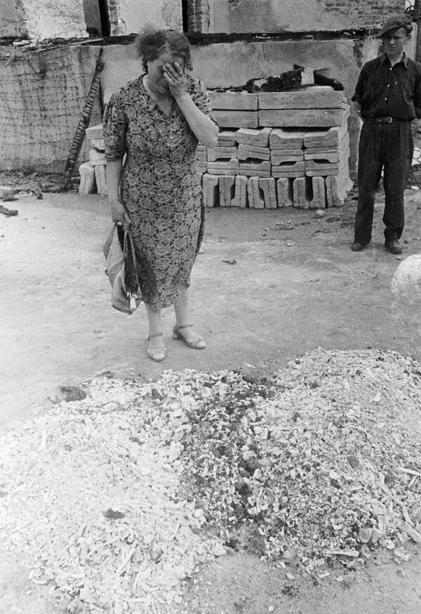 Женщина плачет у праха сожженных людей в печах лагеря смерти Майданека в польском Люблине, 1944 год - Sputnik Южная Осетия