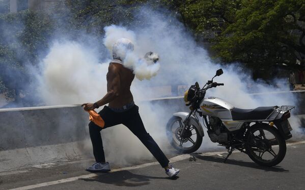 Протестующий кидает бутылку со слезоточивым газом во время столкновения с Национальной гвардией Венесуэлы в Альтамире, районе Каракаса - Sputnik Южная Осетия