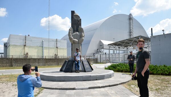 Туристы фотографируются возле памятника ликвидаторам аварии на Чернобыльской атомной электростанции имени Владимира Ильича Ленина  во время экскурсии в зону отчуждения в городе Чернобыль - Sputnik Южная Осетия