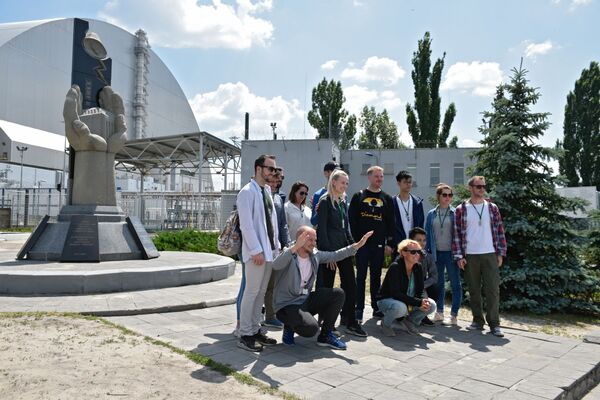 Туристы фотографируются возле памятника ликвидаторам аварии на ЧАЭС  во время экскурсии в зону отчуждения в городе Чернобыль - Sputnik Южная Осетия