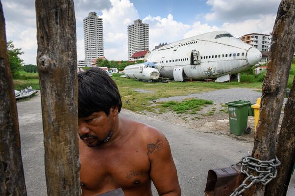 Мужчина у ворот перед брошенным самолетом в пригороде Бангкока - Sputnik Южная Осетия