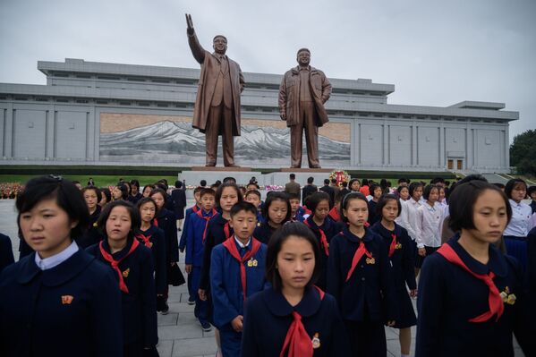 Студенты у статуй северокорейских лидеров Ким Ир Сена и Ким Чен Ира выражают свое почтение по случаю 74-й годовщины основания Рабочей партии Кореи, КНДР - Sputnik Южная Осетия
