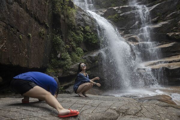 Женщина позирует фотографу у водопада в Уишане в восточной китайской провинции Фуцзянь - Sputnik Южная Осетия