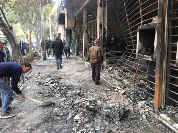 Прохожие у сожженного здания банка после протестов в Эсфахане  - Sputnik Южная Осетия