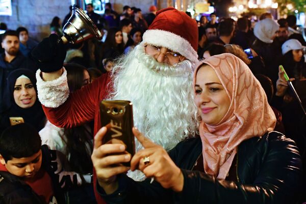 Женщина фотографируется с мужчиной в костюме Санта-Клауса на праздновании Рождества в сирийской Латакии - Sputnik Южная Осетия